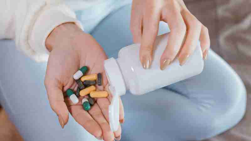 Close-up of hands pouring mixed capsules from a pill bottle indoors, focusing on healthcare and medicine., tags: informierte entscheidungen - pexel
